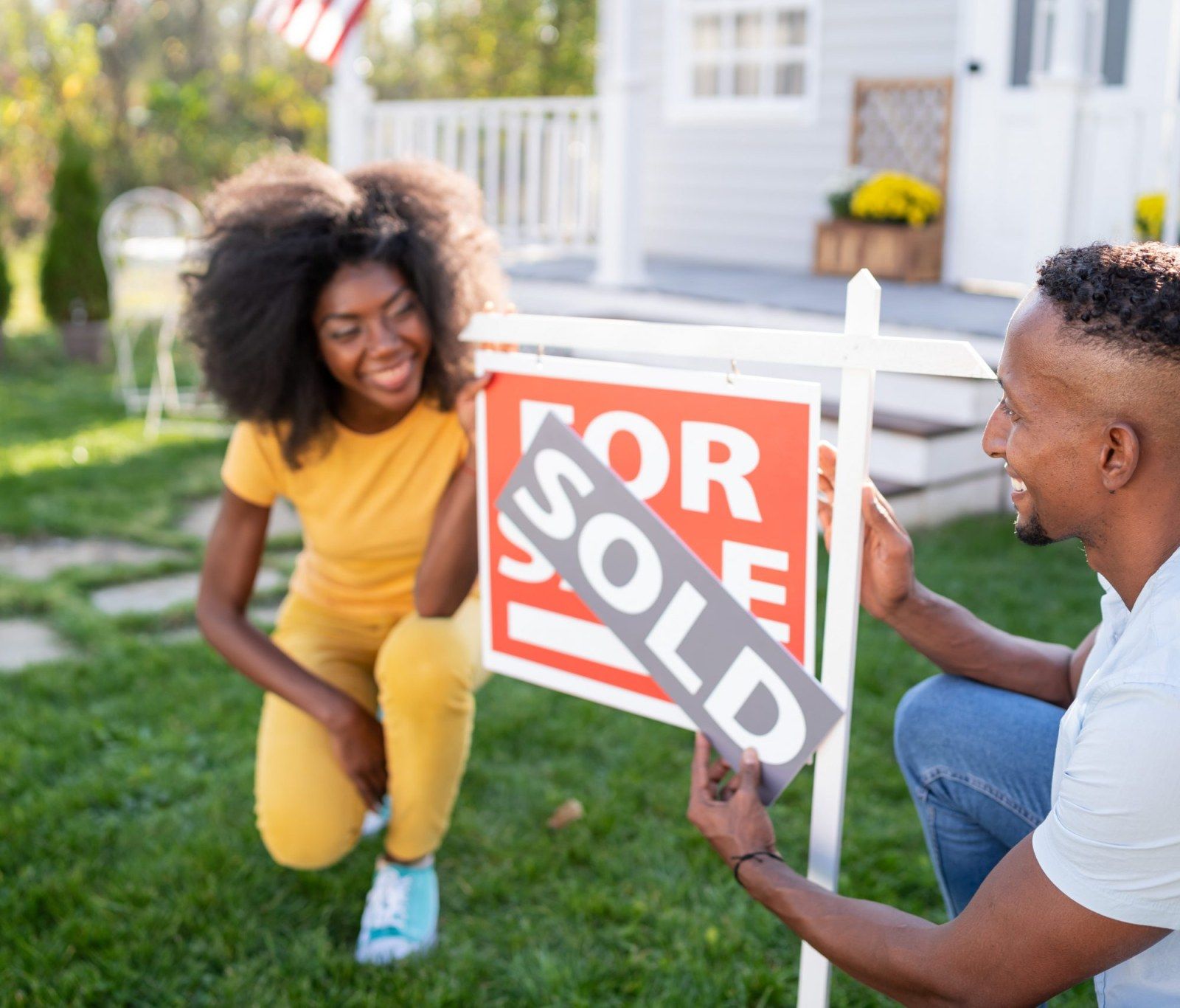 Couple putting sold sign in front of their new home