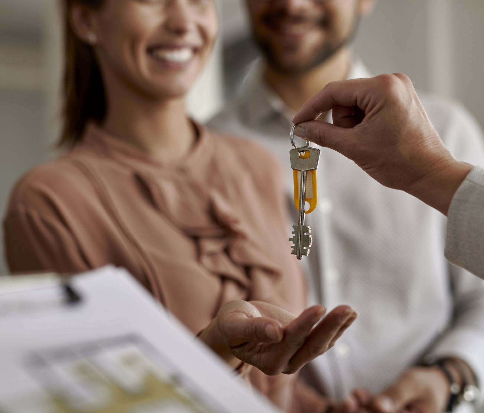 Real estate agent giving new house keys to a couple.
