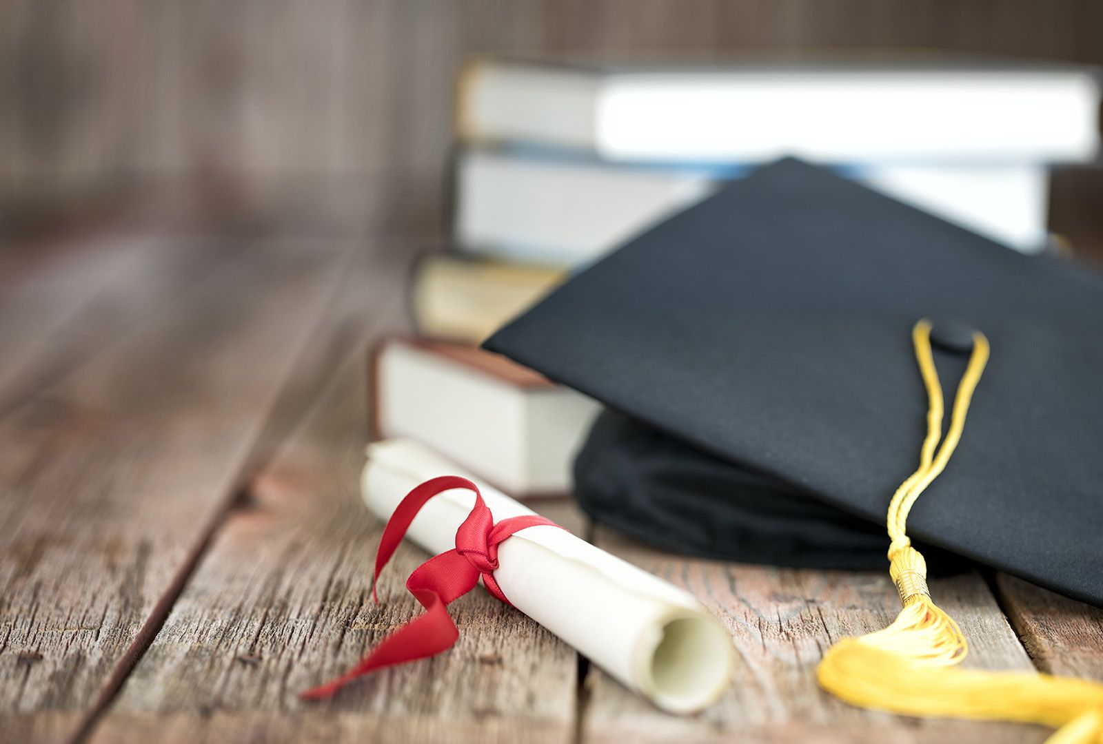 A mortarboard and rolled-up degree on a table