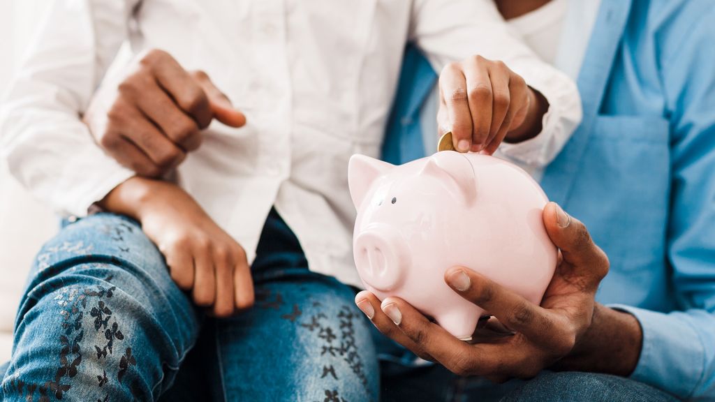child putting coins into a piggy bank